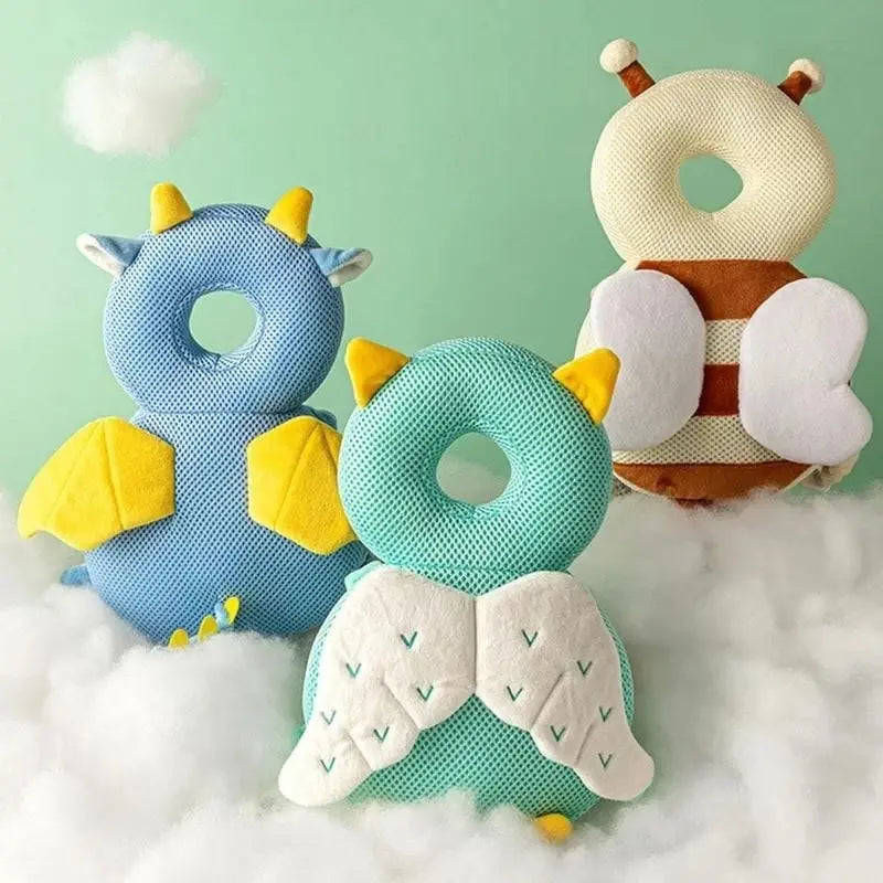 Colorful fantasy-themed baby travel cushions shaped like animals and dragons, designed to protect babies’ heads during falls, displayed on a soft cloud background.